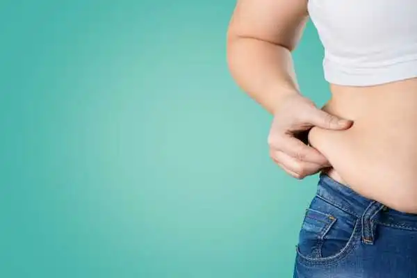 Image of woman pinching her love handles to show weight gain Oxshott